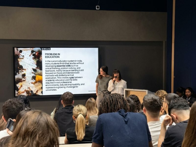 Two speakers present to a room full of students. On screen, “Problem in education”: the gap between academic training and the skills real work demands.
